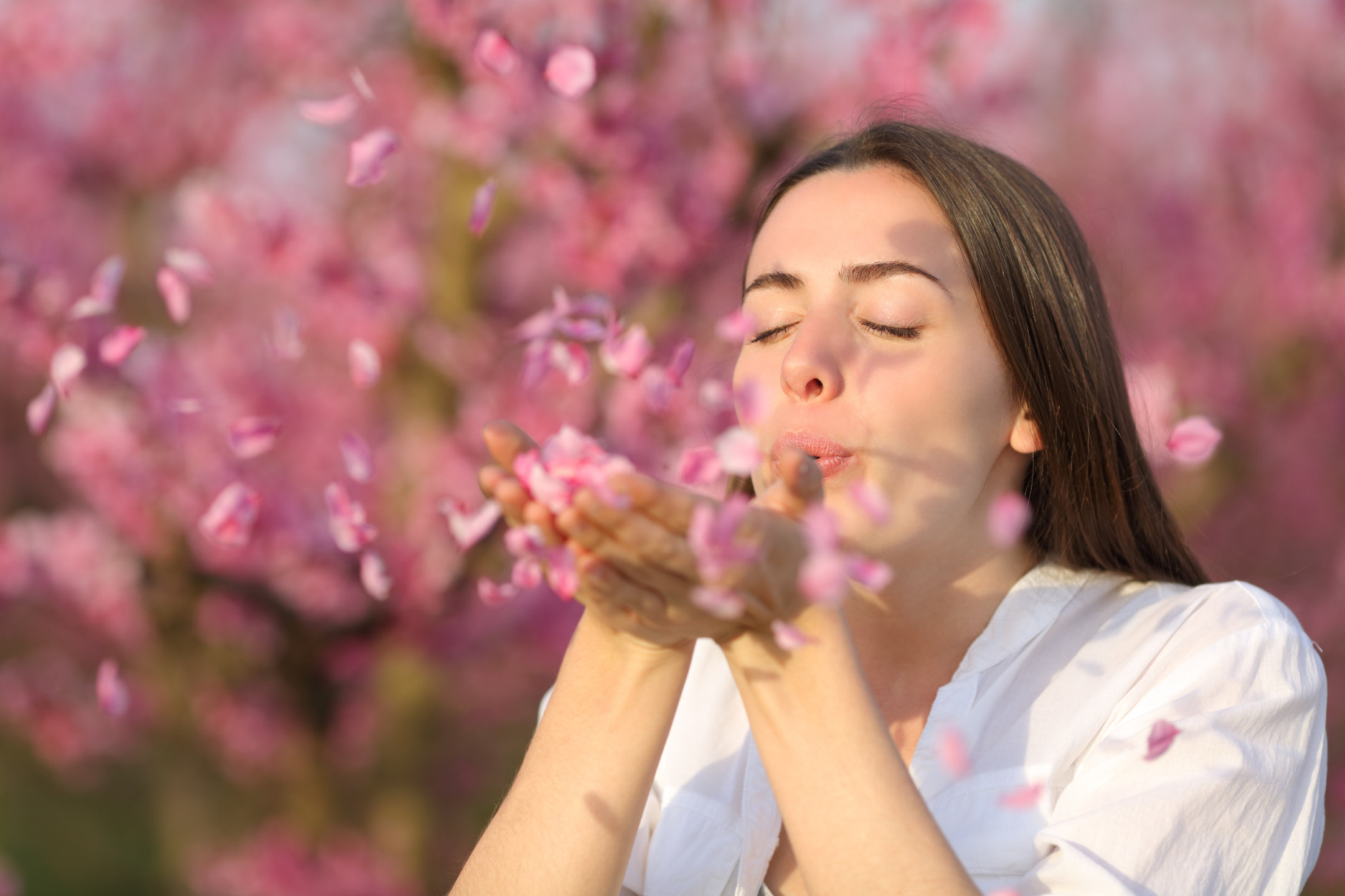 Woman blowing flower petals from her hands in spring